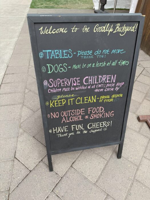 a Black Sandwich Board Sign on a Stone Path Displays Colorful Chalk Writing with Rules Tablesplease Do Not Move Dogsmust Be Leashed Supervise Children Keep It Clean No Outside Food Alcohol or Smoking and Ends with Have Fun Cheers a Black Sandwich Board Sign on a Stone Path Displays Colorful Chalk Writing with Rules Tablesplease Do Not Move Dogsmust Be Leashed Supervise Children Keep It Clean No Outside Food Alcohol or Smoking and Ends with Have Fun Cheers