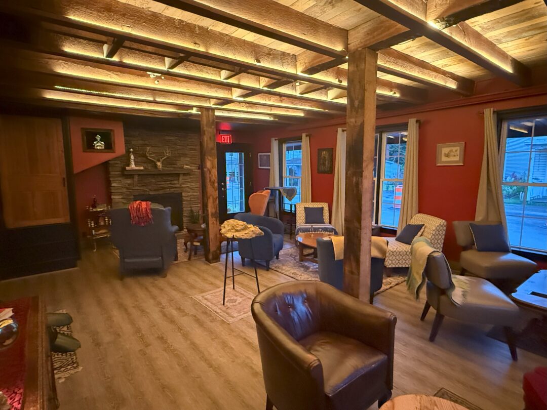Cocktail bar market table bistro a Cozy Lounge at Market Table Bistro Features Wooden Beams Red Walls and Floor Lamps Armchairs and Small Tables Sit on Rugs a Stone Fireplace and Bookshelves Add Warmth While Large Windows and Draped Blankets Create a Welcoming Relaxed Atmosphere