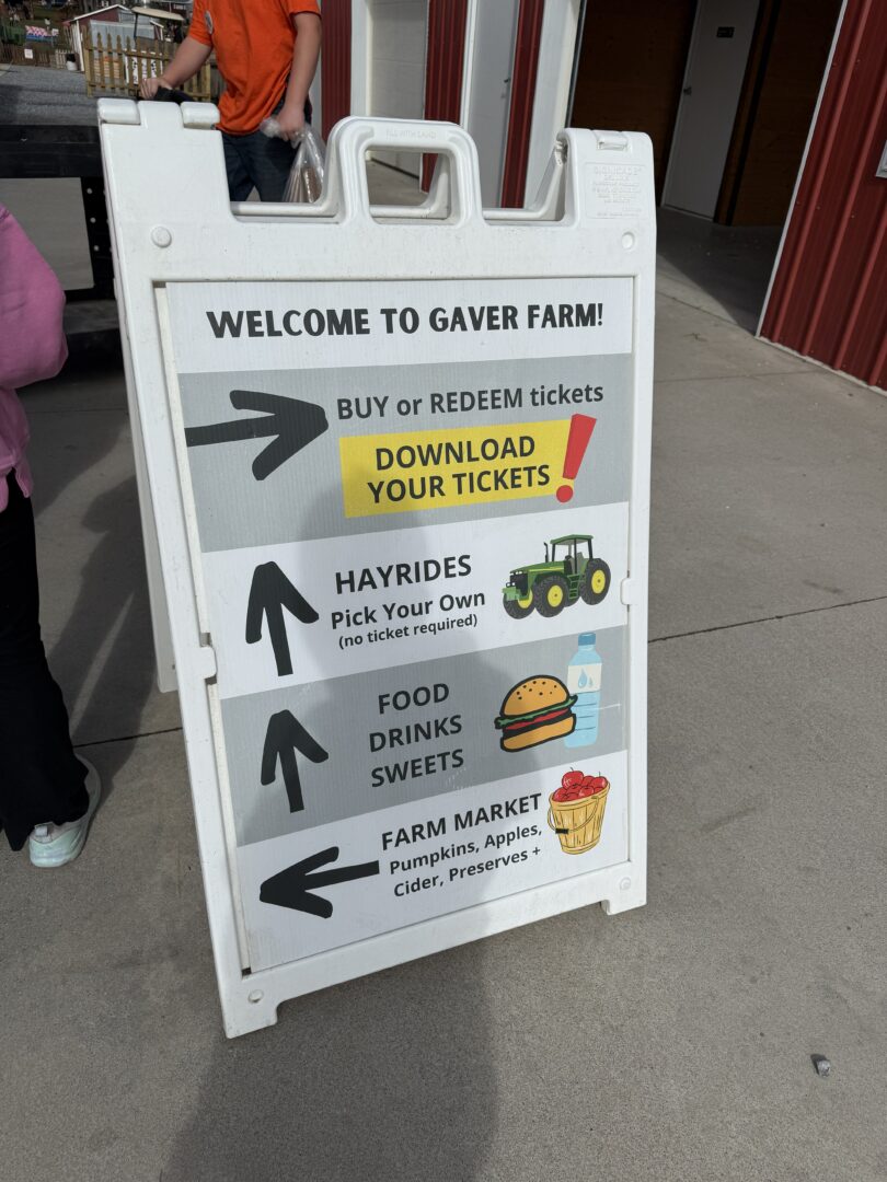 Entrance sign gaver farms a White Sandwich Board Sign at Gaver Farm Lists Directions Buy or Redeem Tickets Hayrides with a Tractor Icon Food Drinks and Sweets with Icons and the Gaver Farm Market with Pumpkin and Preserves Symbols