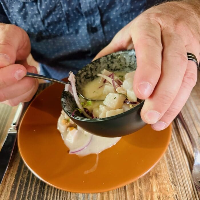 Close up of Hands Handling a Spoon over a Bowl of Diced Onions and Creamy Sauce on a Wooden Table a Person Wears a Ring on One Finger