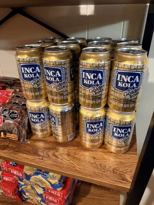 Rows of Inca Kola the Golden Kola Cans Lined Up on Store Shelf in Gold and Blue Labels