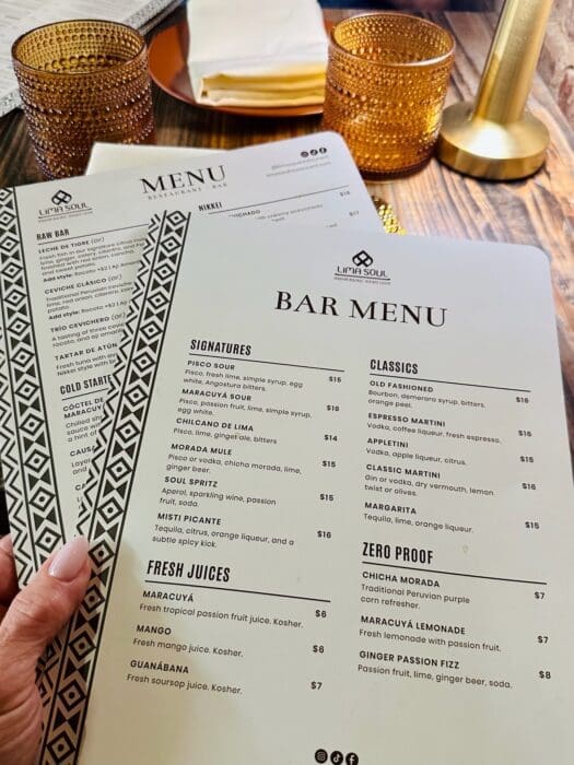 Bar Menu from Lima Soul on a Wooden Table with Two Amber Textured Glasses and a Tissue Packet in the Background