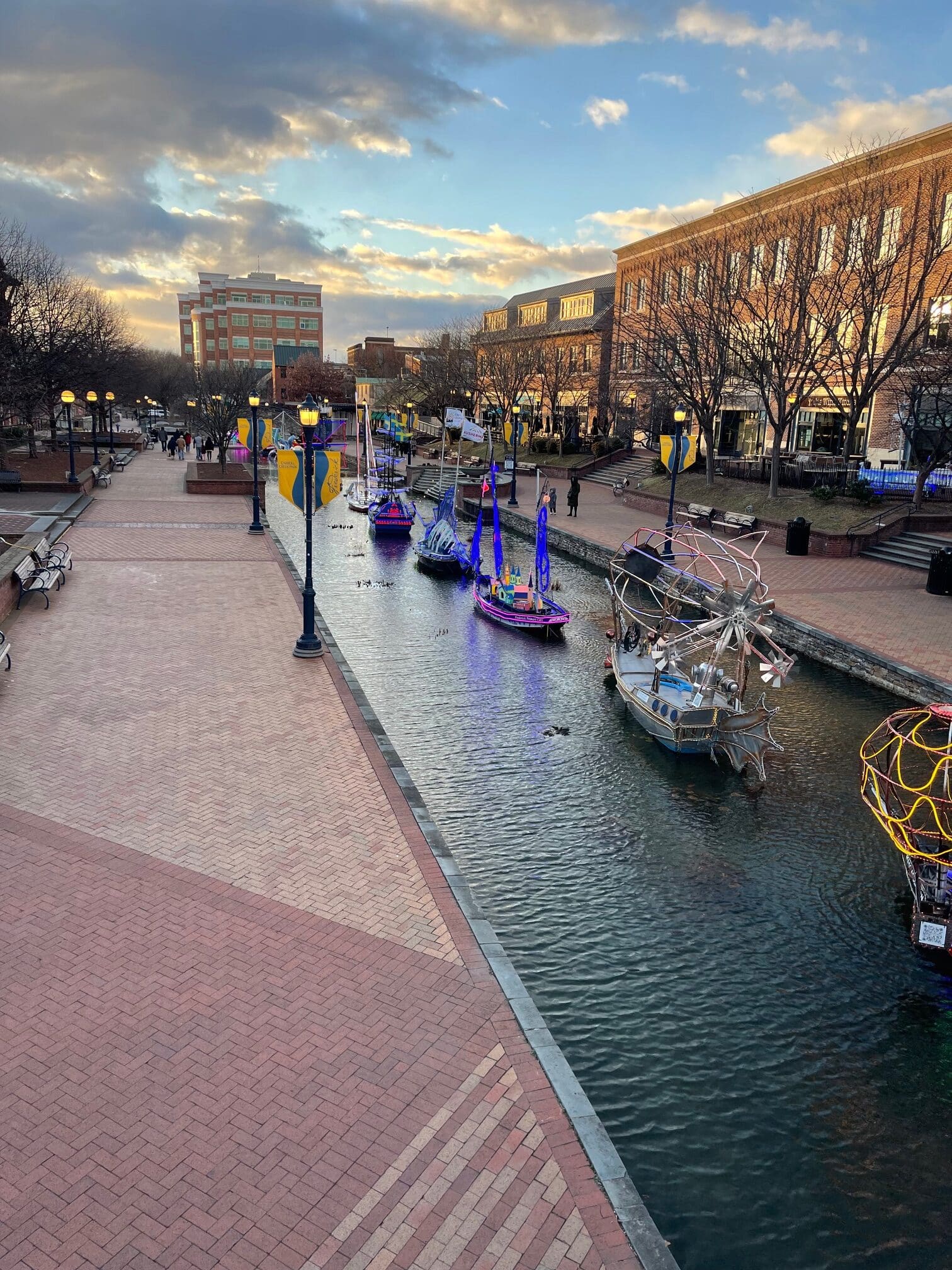 Canal in a City with Colorful Moored Boats Along a Brick Pedestrian Walkway at Sunsetsunlit Late Afternoon