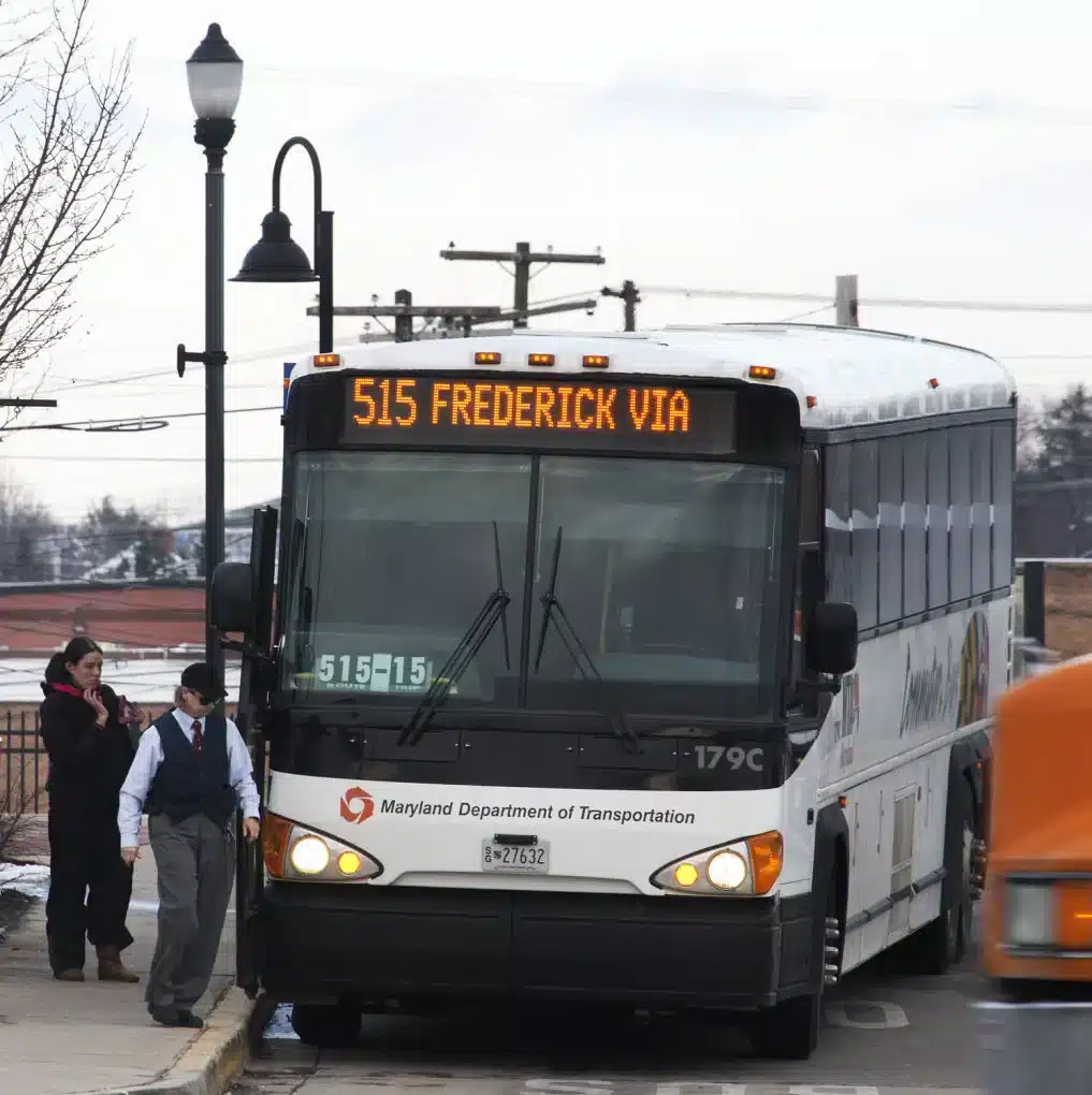 Maryland Department of Transportation Bus Stopped at a Curb Displaying Route 515 to Frederick on Its Front Sign with Two People Nearby