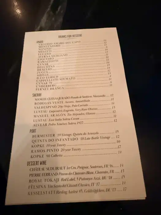 Angle View of a Printed Menu on a Dark Table Header drinks for Dessert with Wine List and Prices