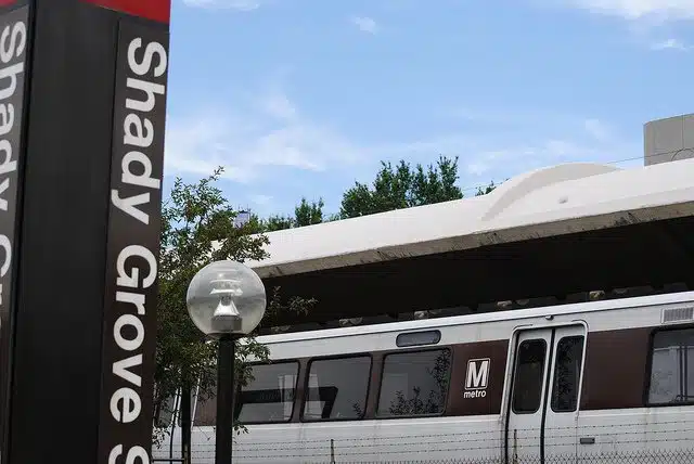Silver Metro Train at Shady Grove Station Platform Under a Blue Sky with a Vertical Shady Grove Sign Nearby