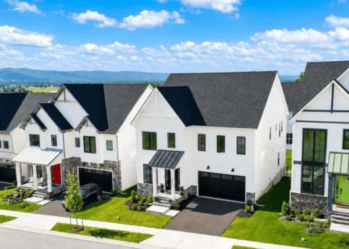 Row of modern white townhouses with attached garages on a sunny street.