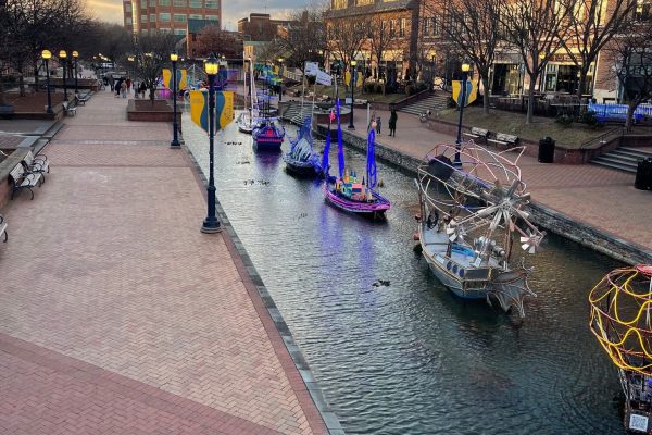 Canal in a city with colorful moored boats along a brick pedestrian walkway at sunset/sunlit late afternoon.