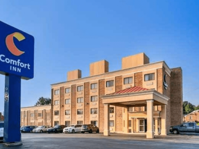 Comfort Inn hotel exterior with a blue sign and a covered entrance, parking lot in front under a clear blue sky