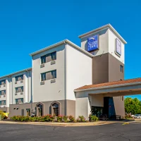 sleep-inn-frederick-ballenger-creek Sleep Inn hotel exterior under a clear blue sky, with a driveway and landscaped plants in front.